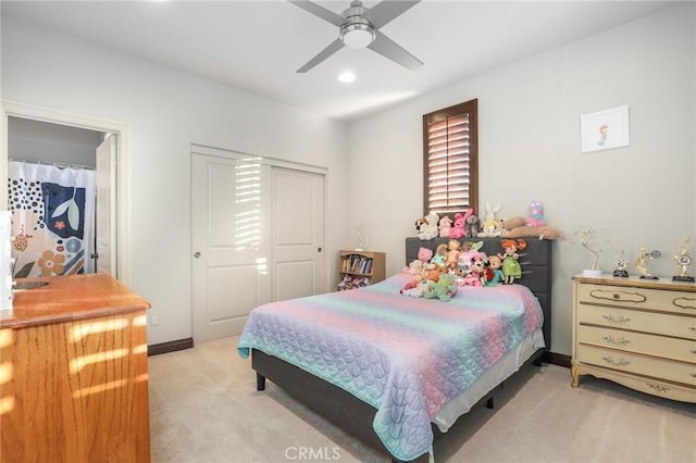 bedroom with light carpet, ceiling fan, a closet, and baseboards