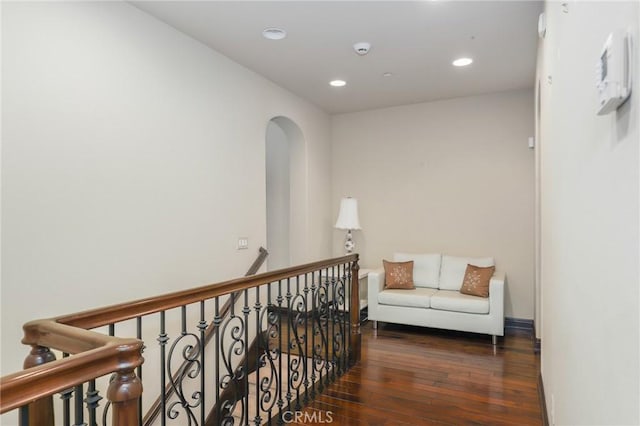 corridor featuring dark wood-type flooring, recessed lighting, arched walkways, and baseboards