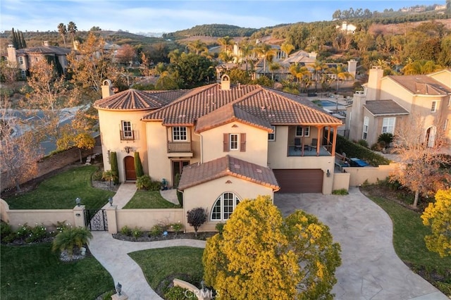 view of front of property featuring a balcony, a garage, a tile roof, concrete driveway, and a gate