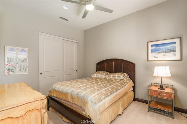 bedroom with ceiling fan, light colored carpet, and a closet