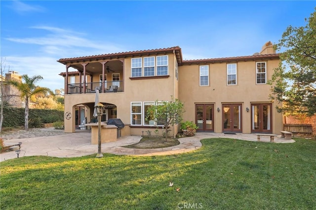 back of property with a patio, a lawn, a balcony, and stucco siding