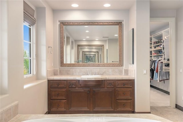 full bath with a walk in closet, tile patterned flooring, vanity, and recessed lighting