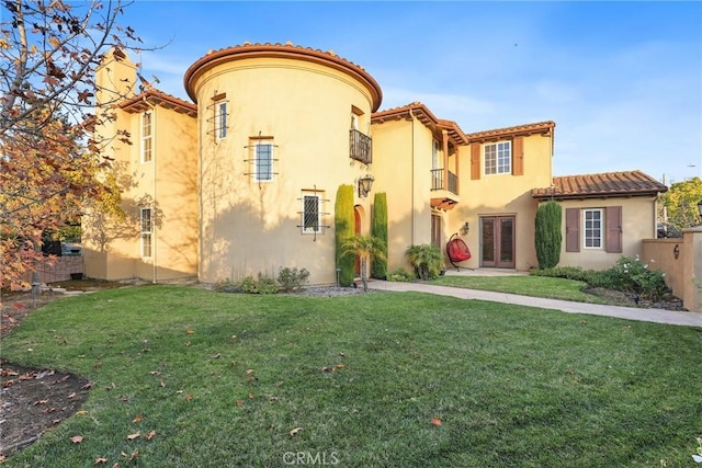 view of front facade featuring french doors, a tile roof, a front lawn, and stucco siding