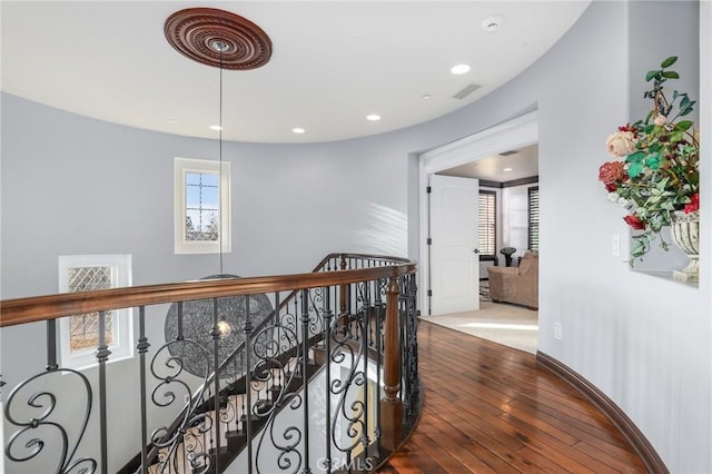 hallway with recessed lighting, a healthy amount of sunlight, an upstairs landing, and wood finished floors