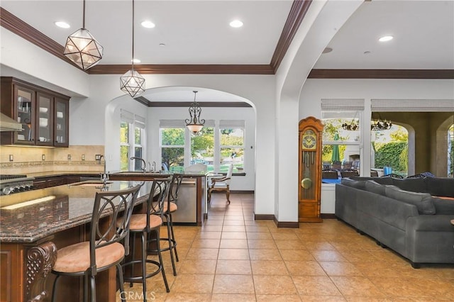 kitchen featuring a breakfast bar area, glass insert cabinets, dark brown cabinets, pendant lighting, and stainless steel dishwasher