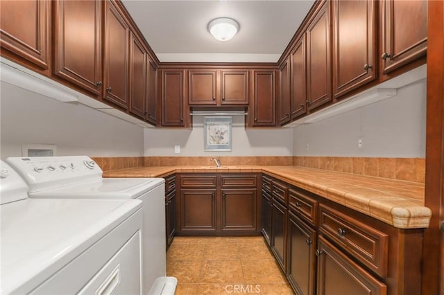 washroom with cabinets, sink, and washing machine and clothes dryer