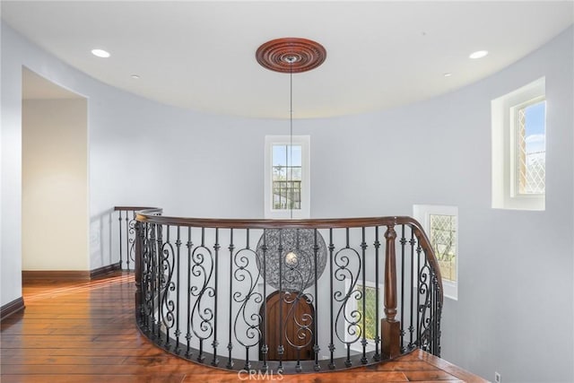 corridor with recessed lighting, baseboards, wood finished floors, and an upstairs landing