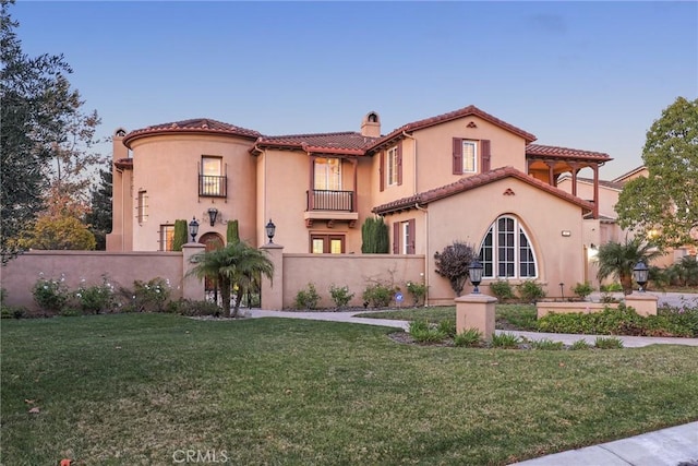 mediterranean / spanish-style house featuring a front lawn and a balcony