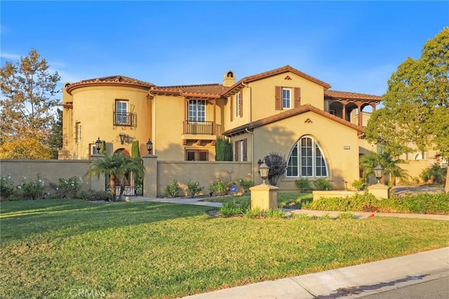 mediterranean / spanish house with a chimney, a balcony, a front lawn, and stucco siding