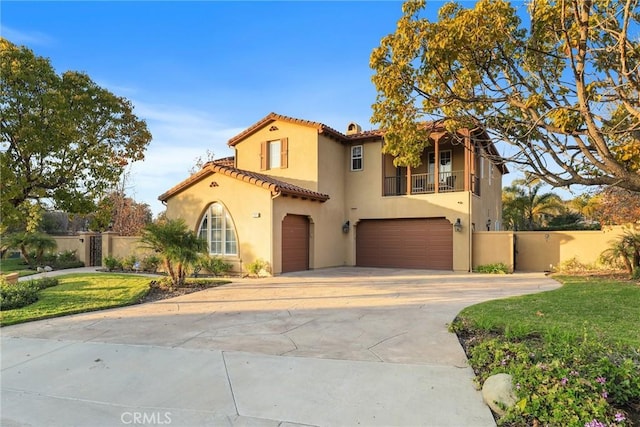 mediterranean / spanish-style house with driveway, a garage, a balcony, fence, and stucco siding