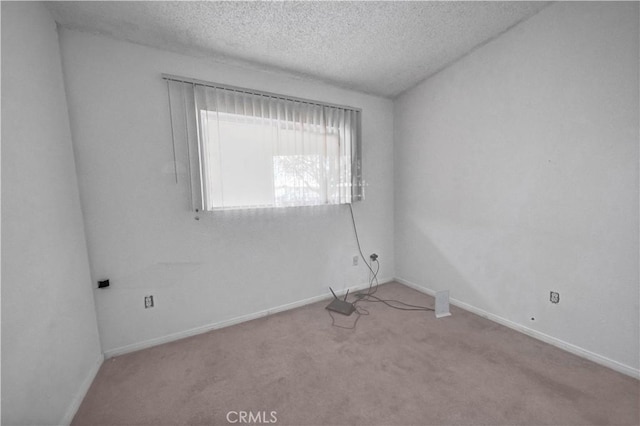 empty room with light colored carpet and a textured ceiling