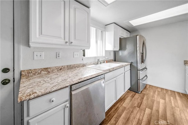 kitchen featuring appliances with stainless steel finishes, light hardwood / wood-style flooring, white cabinetry, and sink