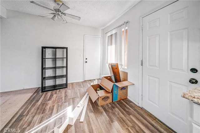 foyer entrance with ceiling fan, wood-type flooring, and a textured ceiling