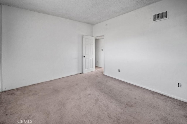 carpeted empty room featuring a textured ceiling