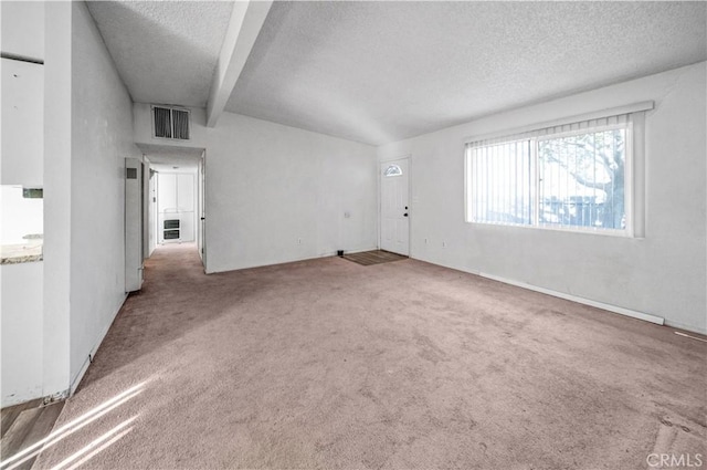 carpeted empty room featuring beam ceiling, a textured ceiling, and heating unit