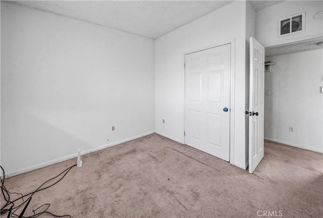 unfurnished bedroom featuring a textured ceiling and light colored carpet