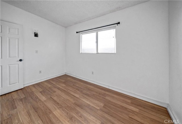 spare room with a textured ceiling and light hardwood / wood-style flooring