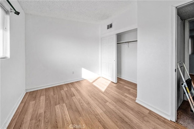 unfurnished bedroom with a textured ceiling and light hardwood / wood-style floors