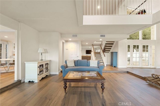 living room featuring a towering ceiling, wood-type flooring, and french doors