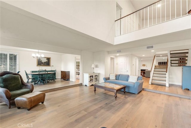 living room featuring an inviting chandelier, a towering ceiling, and hardwood / wood-style floors