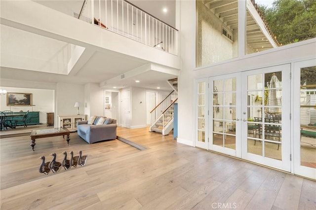 living room featuring french doors, a towering ceiling, and wood-type flooring