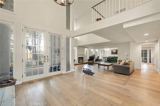 living room with a high ceiling, light hardwood / wood-style floors, and french doors