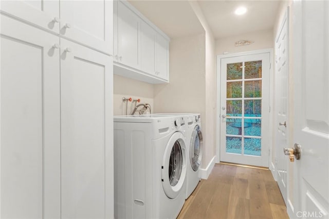 laundry room featuring cabinets, washer and clothes dryer, and light hardwood / wood-style floors