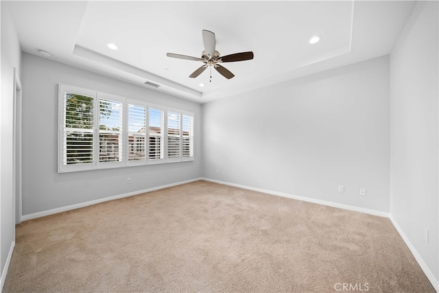 spare room with light carpet, a raised ceiling, and ceiling fan