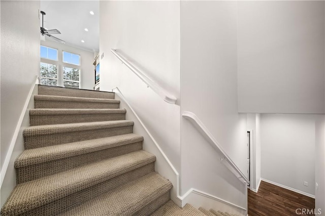 staircase with ceiling fan and hardwood / wood-style flooring