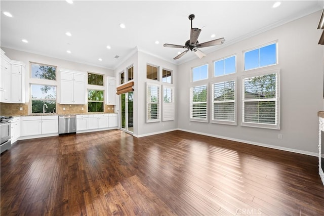 unfurnished living room featuring a wealth of natural light, ceiling fan, dark hardwood / wood-style floors, and ornamental molding