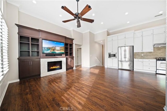 unfurnished living room featuring a stone fireplace, ceiling fan, dark wood-type flooring, and ornamental molding