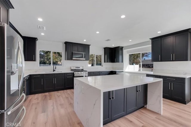 kitchen with a healthy amount of sunlight, sink, stainless steel appliances, and light hardwood / wood-style floors