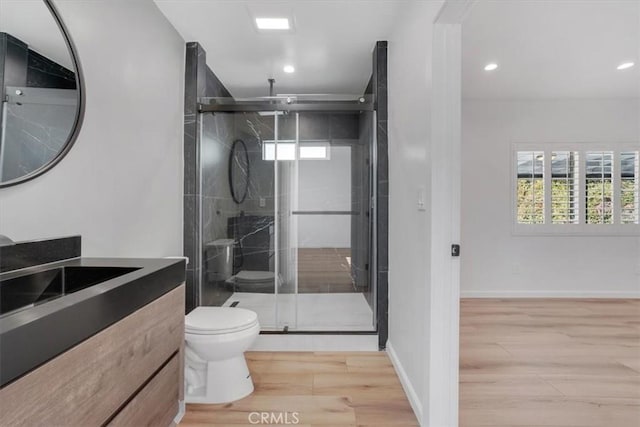 bathroom with hardwood / wood-style flooring, toilet, walk in shower, and vanity