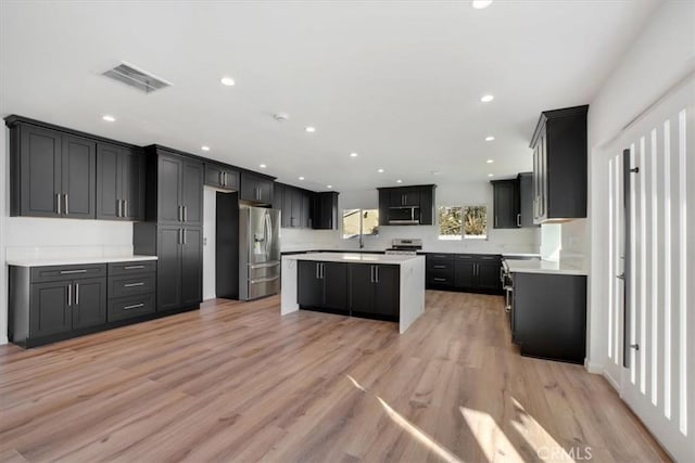 kitchen featuring light wood-type flooring, stainless steel appliances, and a center island