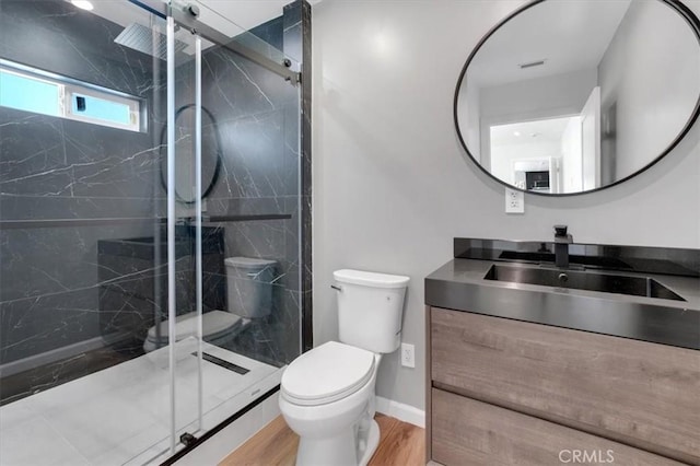 bathroom featuring hardwood / wood-style flooring, toilet, vanity, and a shower with door