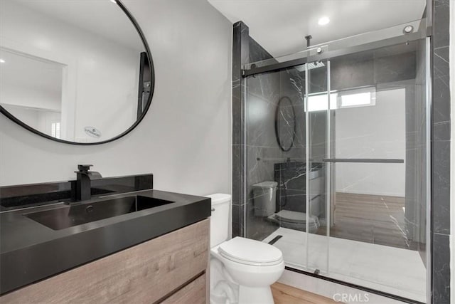 bathroom with vanity, toilet, hardwood / wood-style flooring, and a shower with door