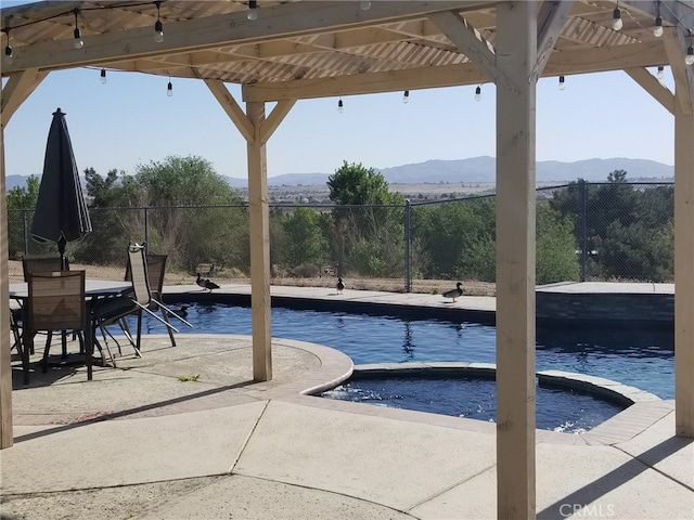 view of swimming pool with an in ground hot tub, a mountain view, and a patio area