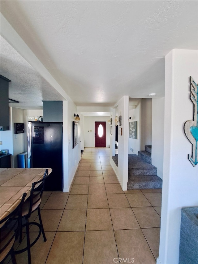 hall with light tile patterned floors and a textured ceiling