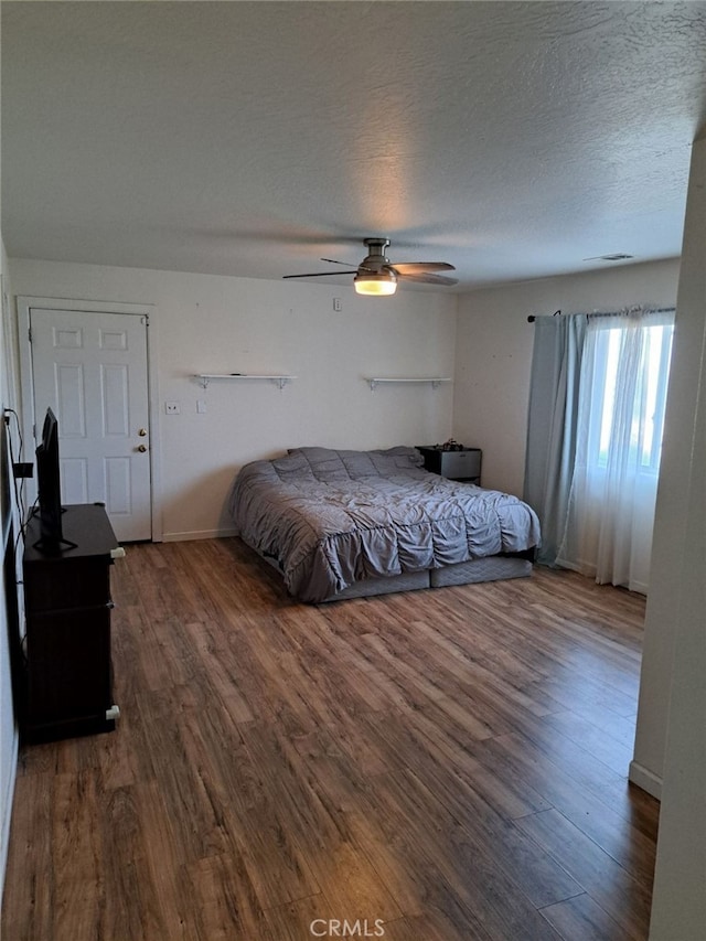 bedroom with ceiling fan, hardwood / wood-style floors, and a textured ceiling