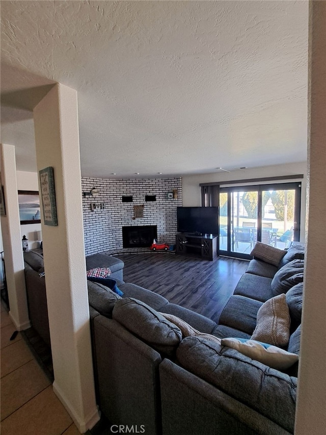 living room featuring a large fireplace, wood-type flooring, and a textured ceiling