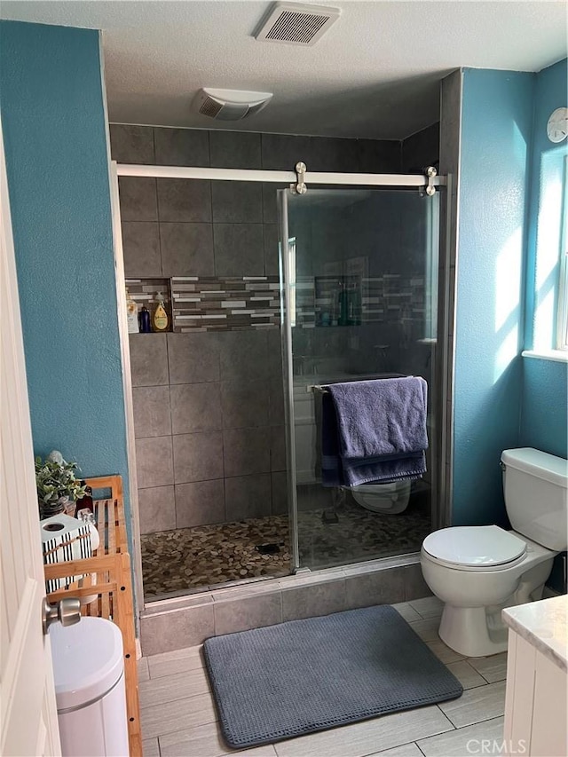 bathroom featuring vanity, walk in shower, a textured ceiling, and toilet