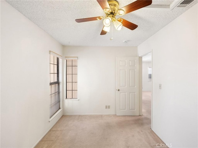 spare room featuring ceiling fan, light colored carpet, and a textured ceiling