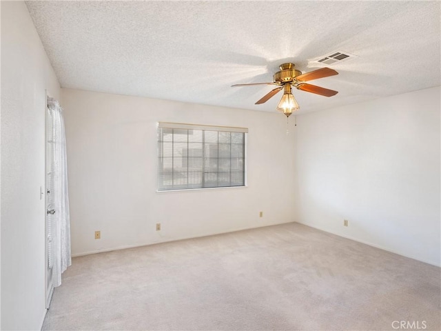 carpeted spare room featuring ceiling fan and a textured ceiling