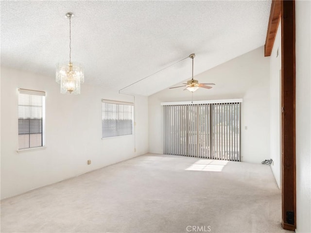 carpeted empty room featuring a textured ceiling, a wealth of natural light, lofted ceiling with beams, and ceiling fan with notable chandelier