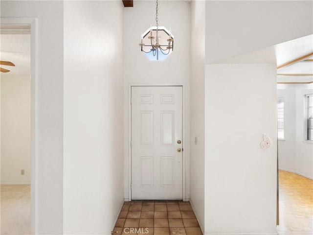 doorway to outside featuring tile patterned floors, a notable chandelier, and a high ceiling