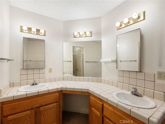 bathroom with backsplash, vanity, and a textured ceiling