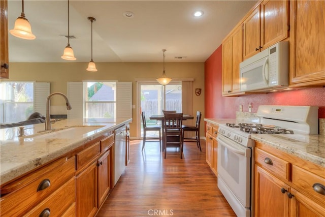 kitchen featuring decorative light fixtures, wood-type flooring, white appliances, and sink