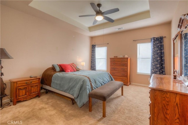 carpeted bedroom featuring a raised ceiling and ceiling fan