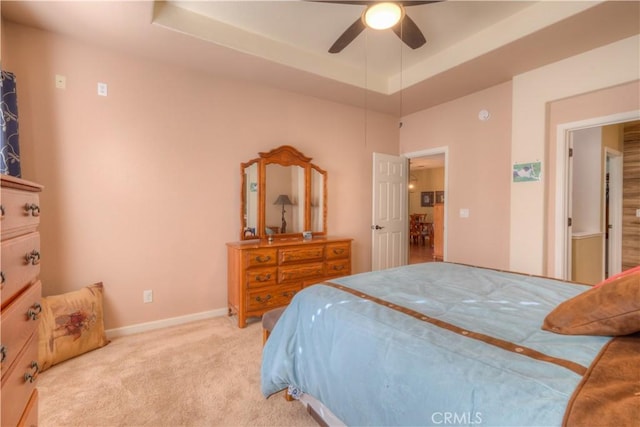 bedroom featuring light carpet, a tray ceiling, and ceiling fan