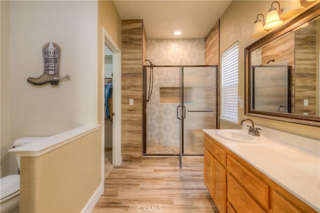 bathroom featuring toilet, vanity, wood-type flooring, and walk in shower